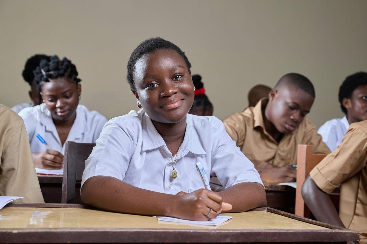 A smiling student writing at her desk