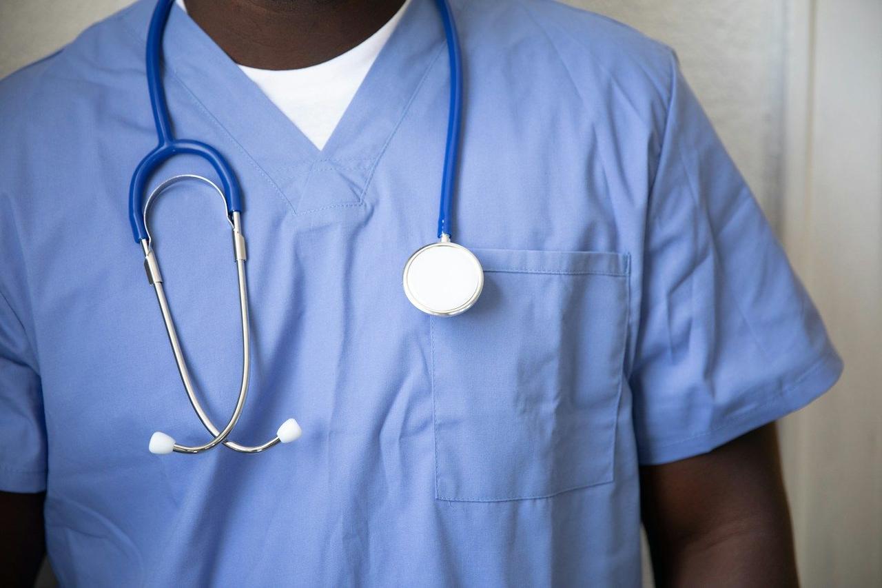 A health worker in blue scrubs with a stethoscope